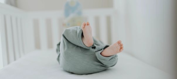 Baby im Gitterbett mit Blick auf die Füße fotografiert